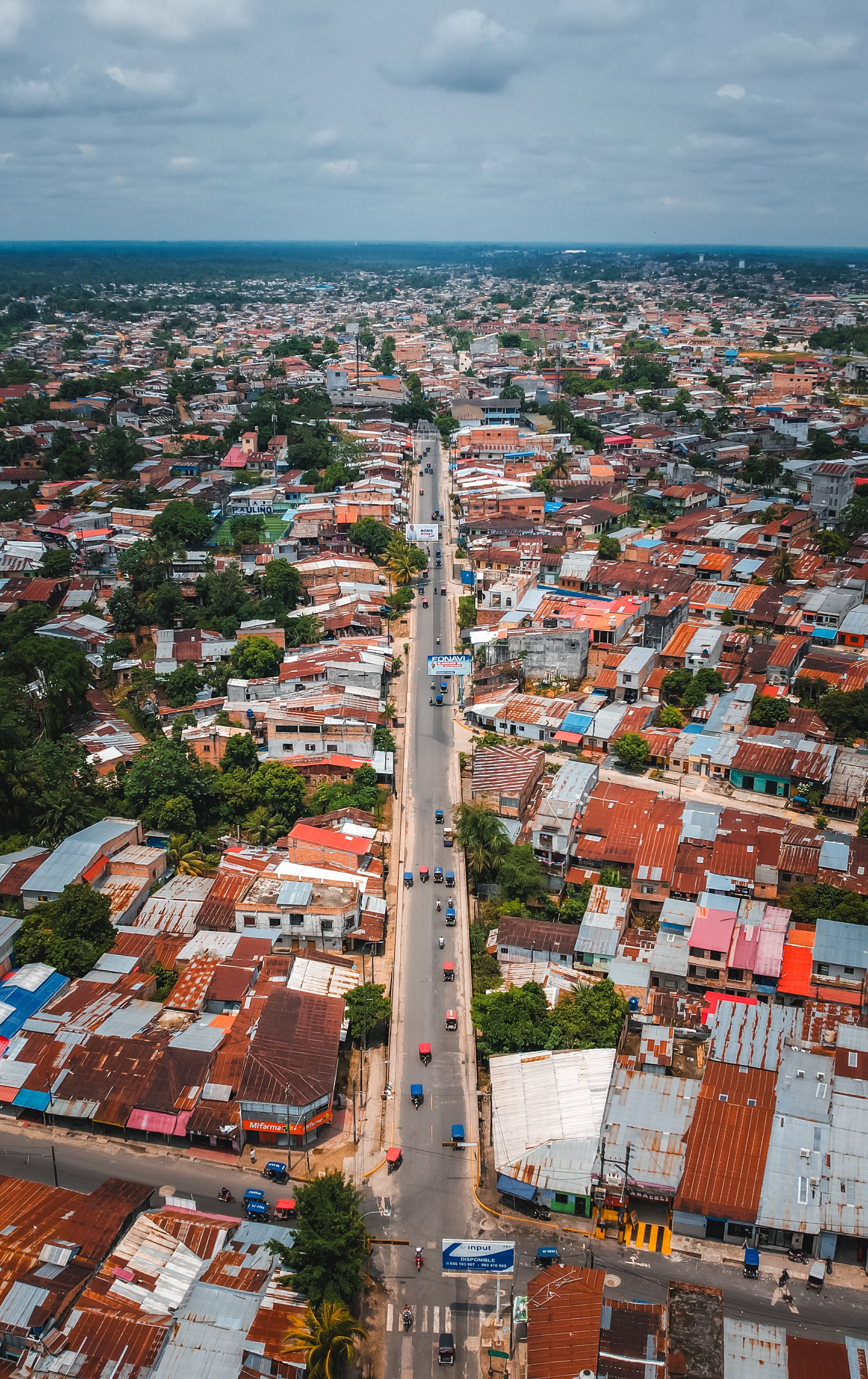 Drone shot capturing the vibrant cityscape of Iquitos, Peru, showcasing urban streets and colorful rooftops.