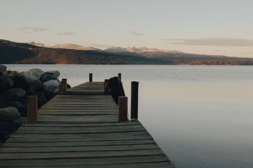 Free Serene scene of a wooden jetty overlooking calm lake waters beneath a peaceful dusk sky. Stock Photo