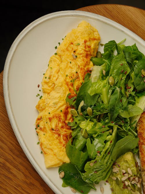 A white plate topped with an omelet and salad