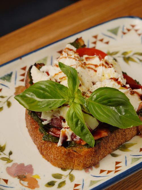 Free Appetizing bruschetta topped with fresh basil, burrata, and balsamic glaze on a decorative plate. Stock Photo