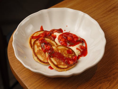 A white plate with pancakes and sauce on it