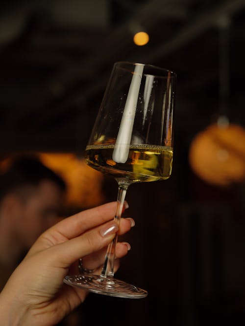 A person holding up a glass of white wine