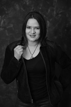 Black and white portrait of a smiling woman in a black jacket with pendant.