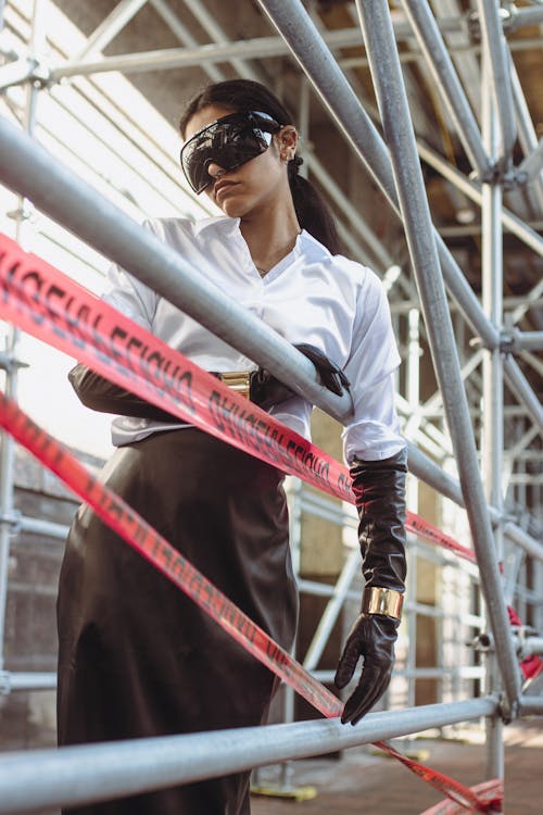 A woman in a black mask and gloves standing next to a fence