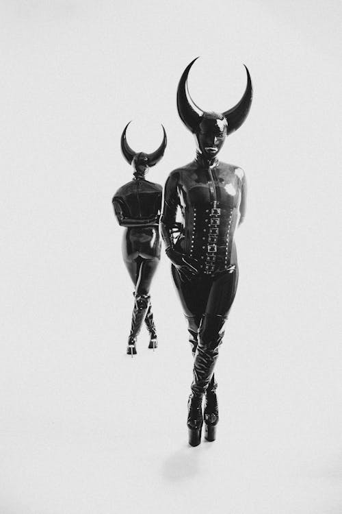Two women in leather and horns walking down a hallway