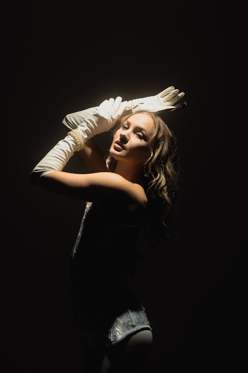 A woman in white gloves posing in the dark