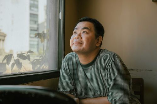 Free A serene moment as a man gazes out of a window in Ho Chi Minh City. Stock Photo