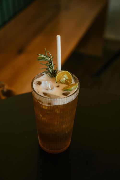 Free Refreshing iced drink with lemon and rosemary on a wooden table, indoor setting, Ho Chi Minh City. Stock Photo