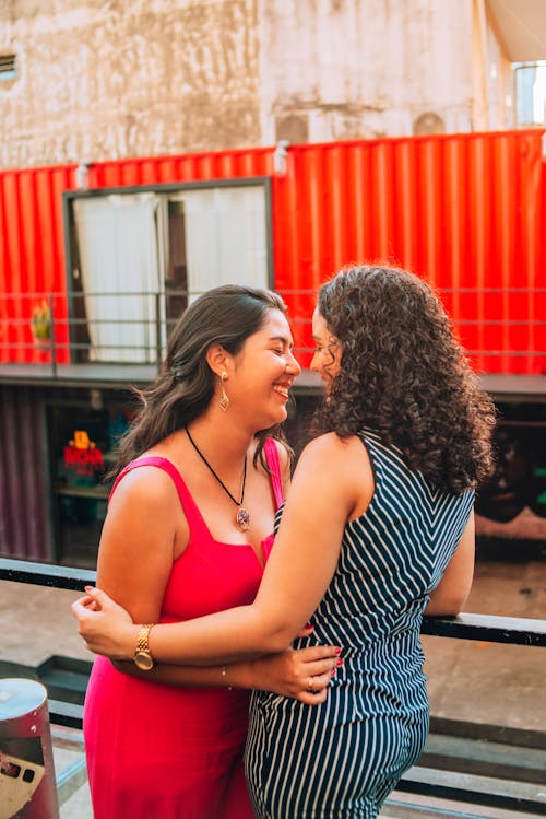 Two women hugging each other in front of a red container
