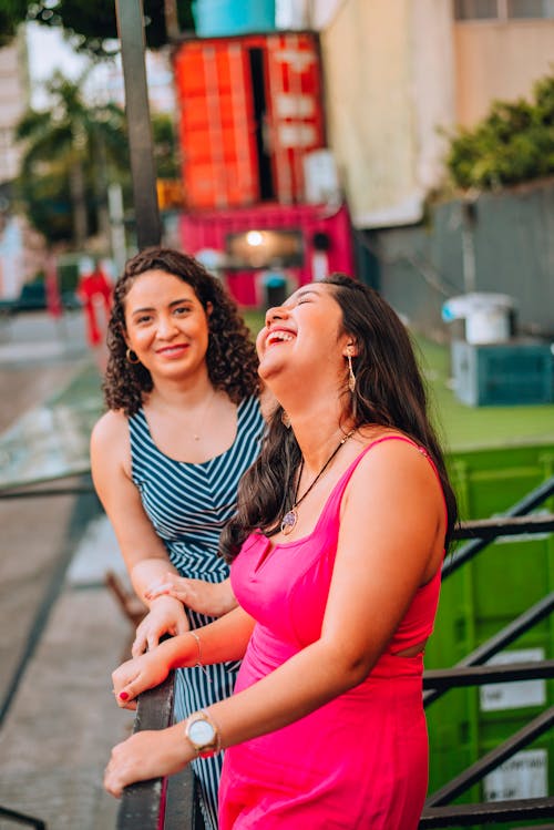 Two women laughing on a street in a city