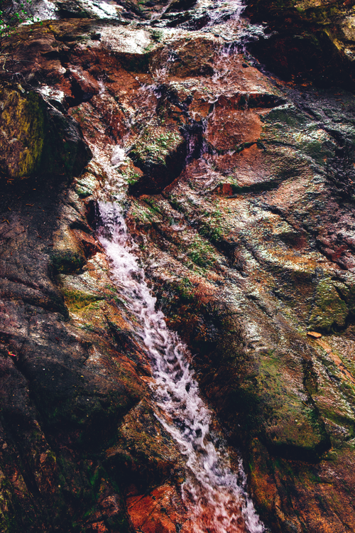 Free A picturesque waterfall cascading down a rocky terrain in a lush English forest. Stock Photo