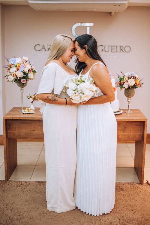 Two women in white dresses hugging each other