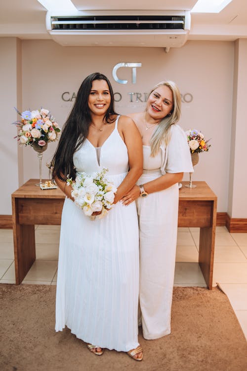 Two women in wedding dresses standing in front of a table