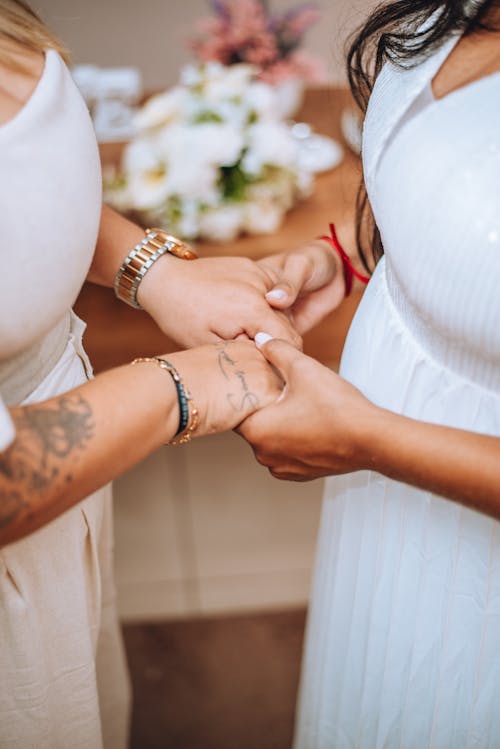 Two women holding hands and one of them is wearing a wedding ring