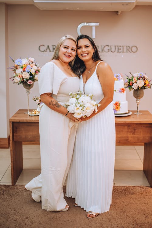 Two women in white dresses standing next to each other