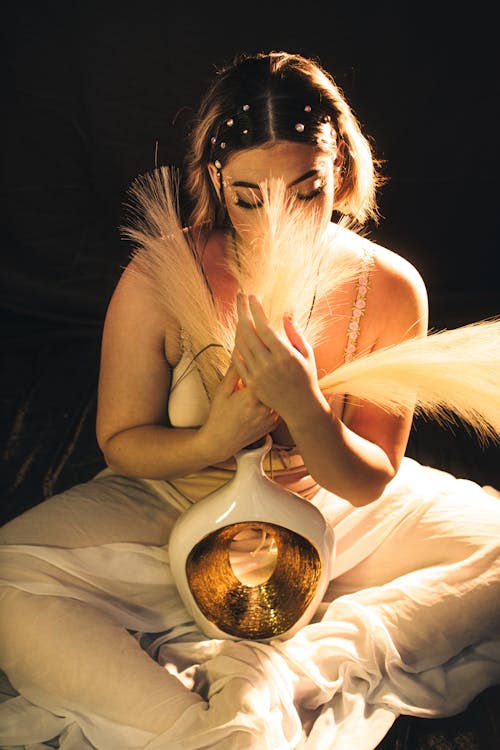 A woman in white holding a bowl with feathers