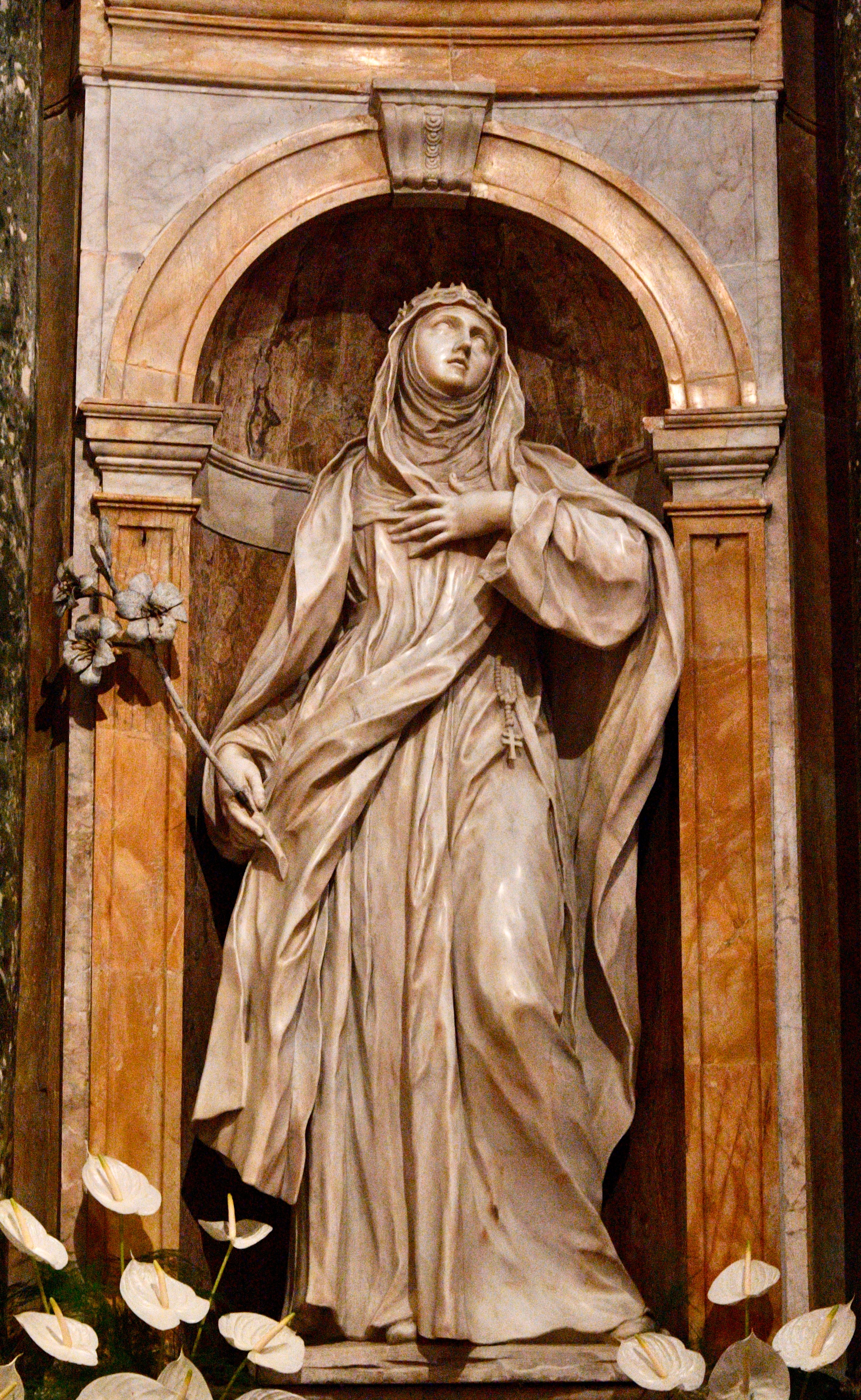 Detailed marble statue of a saint in an ornate church alcove, capturing religious artistry.