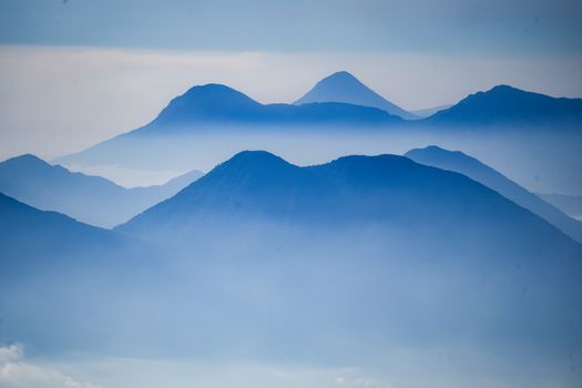 Captivating layers of misty blue mountain ranges at Acatenango, Guatemala, creating a serene and mystical atmosphere.