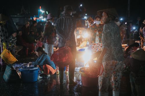 Free A bustling night market scene with people carrying baskets, illuminated by lights. Stock Photo