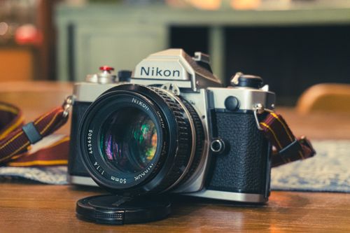 Free Close-up of a classic Nikon film camera with lens cap, ideal for photography enthusiasts. Stock Photo