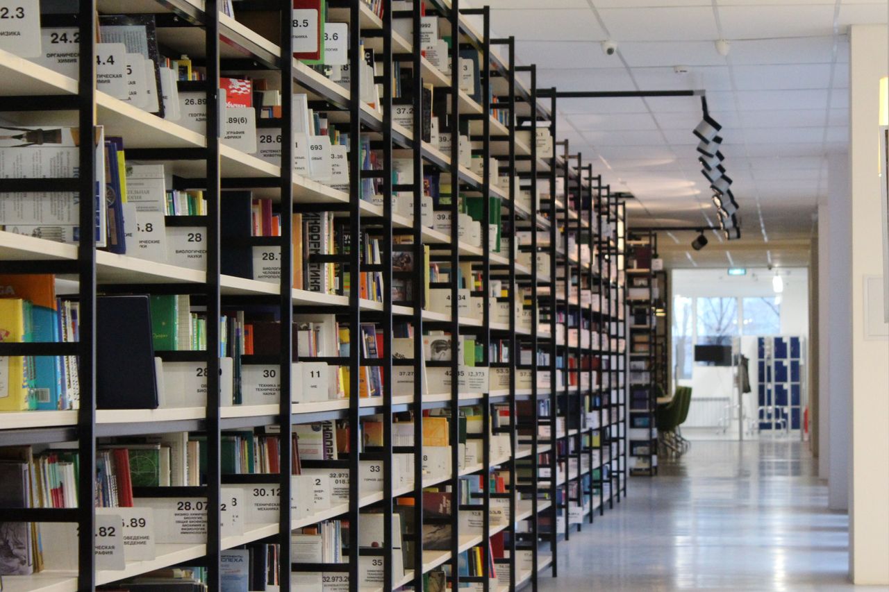 A spacious modern library with organized bookshelves and a well-lit aisle.