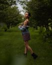 一位穿着花卉连衣裙的时尚女士在公园的郁郁葱葱绿地中享受宁静的拍照时光