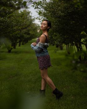 一位穿着花卉连衣裙的时尚女士在公园的郁郁葱葱绿地中享受宁静的拍照时光