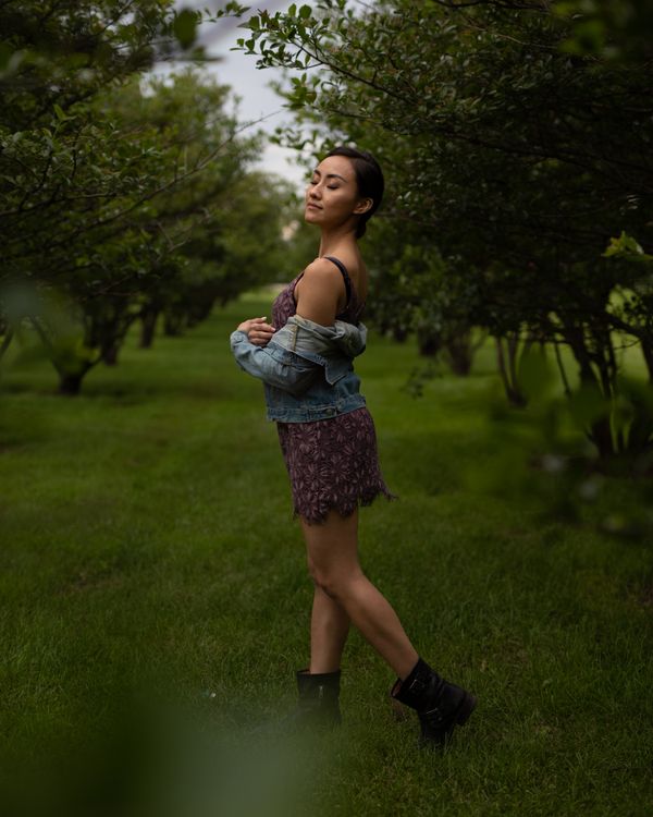 Woman in a floral midi dress layered with a denim jacket in a spring park