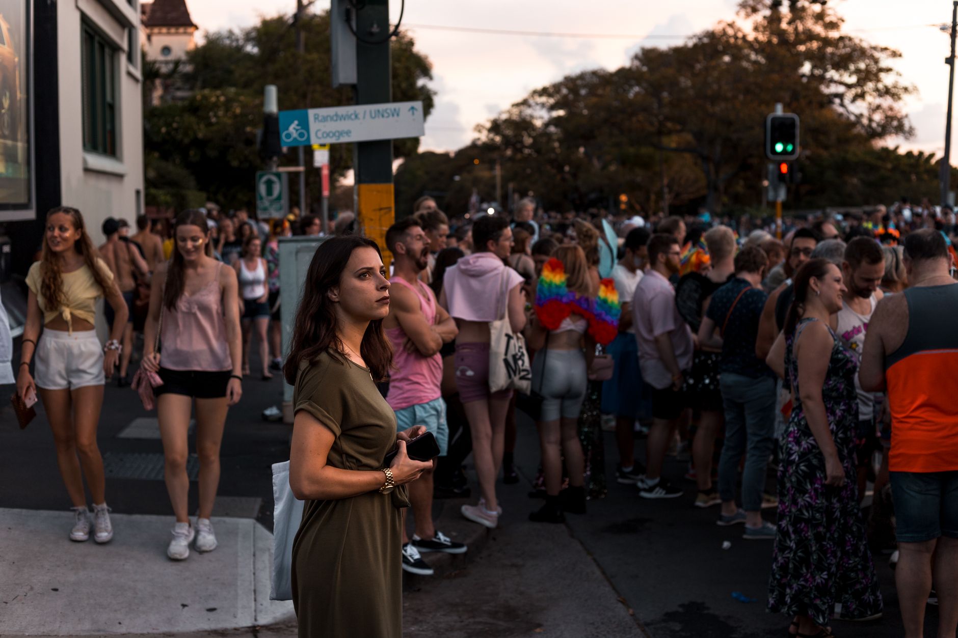 People gathering at an outdoor festival intersection, featuring vibrant outfits and colorful surroundings.