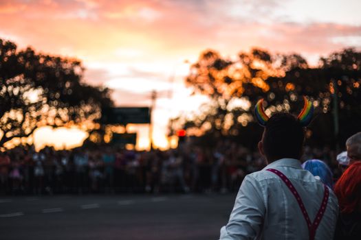 Captivating scene of a crowd at a LGBTQ+ parade with vibrant sunset.