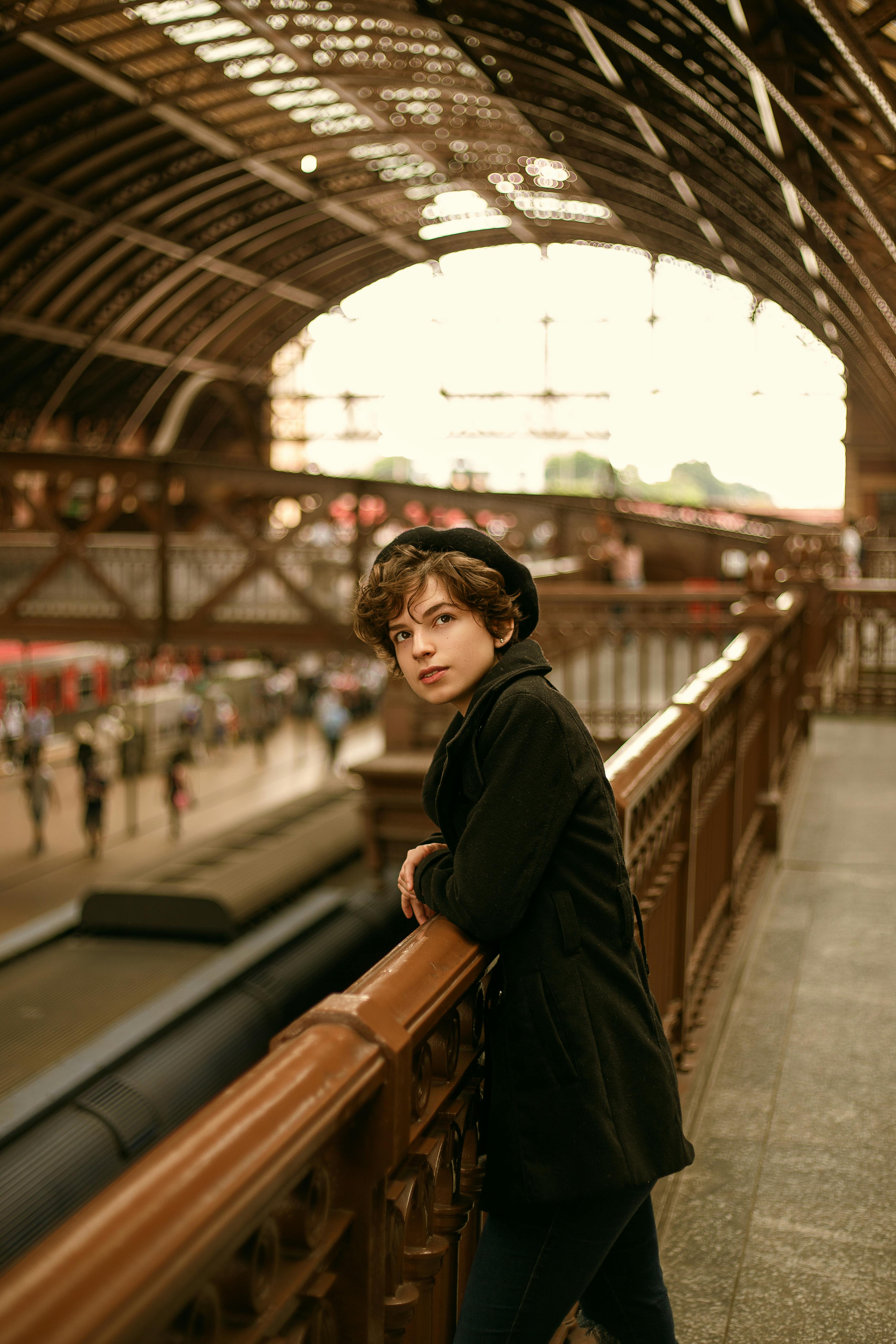 年轻人在历史悠久的火车站靠在栏杆上，展示建筑之美