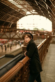 年轻人在历史悠久的火车站靠在栏杆上，展示建筑之美