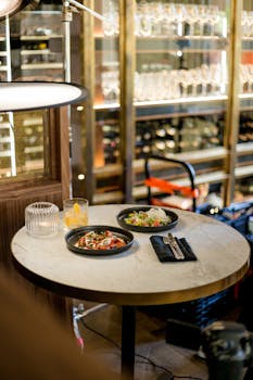 A stylish restaurant table with gourmet dishes and drinks in a modern interior setting.
