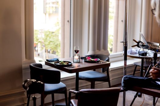 A modern dining table with food, wine, and a city view from a large window.