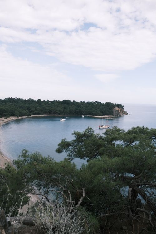 Free A serene bay in Antalya, Turkey with boats anchored and lush pine trees framing the view. Stock Photo