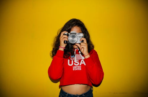 Foto De Uma Mulher Vestindo Um Top Vermelho Cortado Segurando A Câmera Tirando Uma Foto