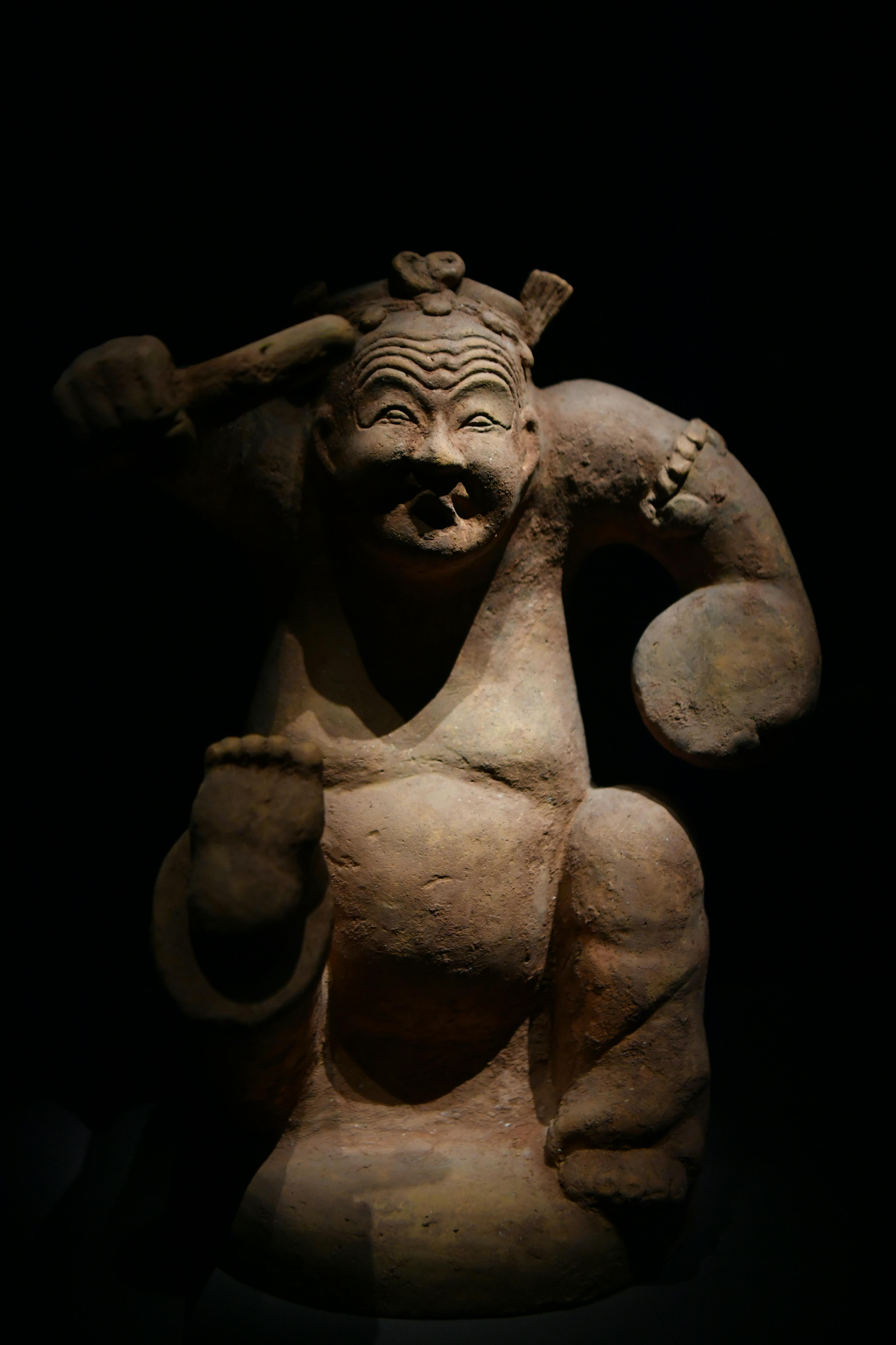 A traditional clay statue in deep shadow, showcasing ancient Chinese art.