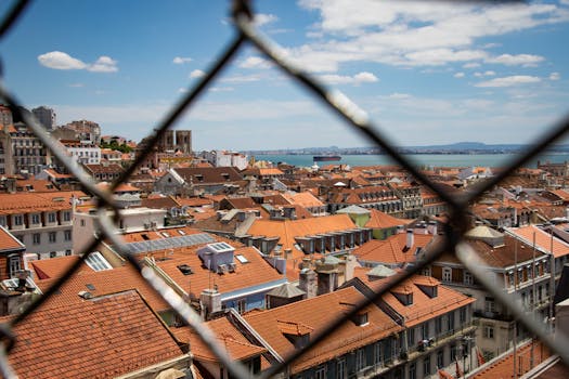 Aerial view of Lisbon's terracotta rooftops and the Tagus River on a sunny day.