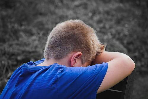 Foto Del Primo Piano Del Bambino Triste Che Si Appoggia Su Una Sedia Di Legno