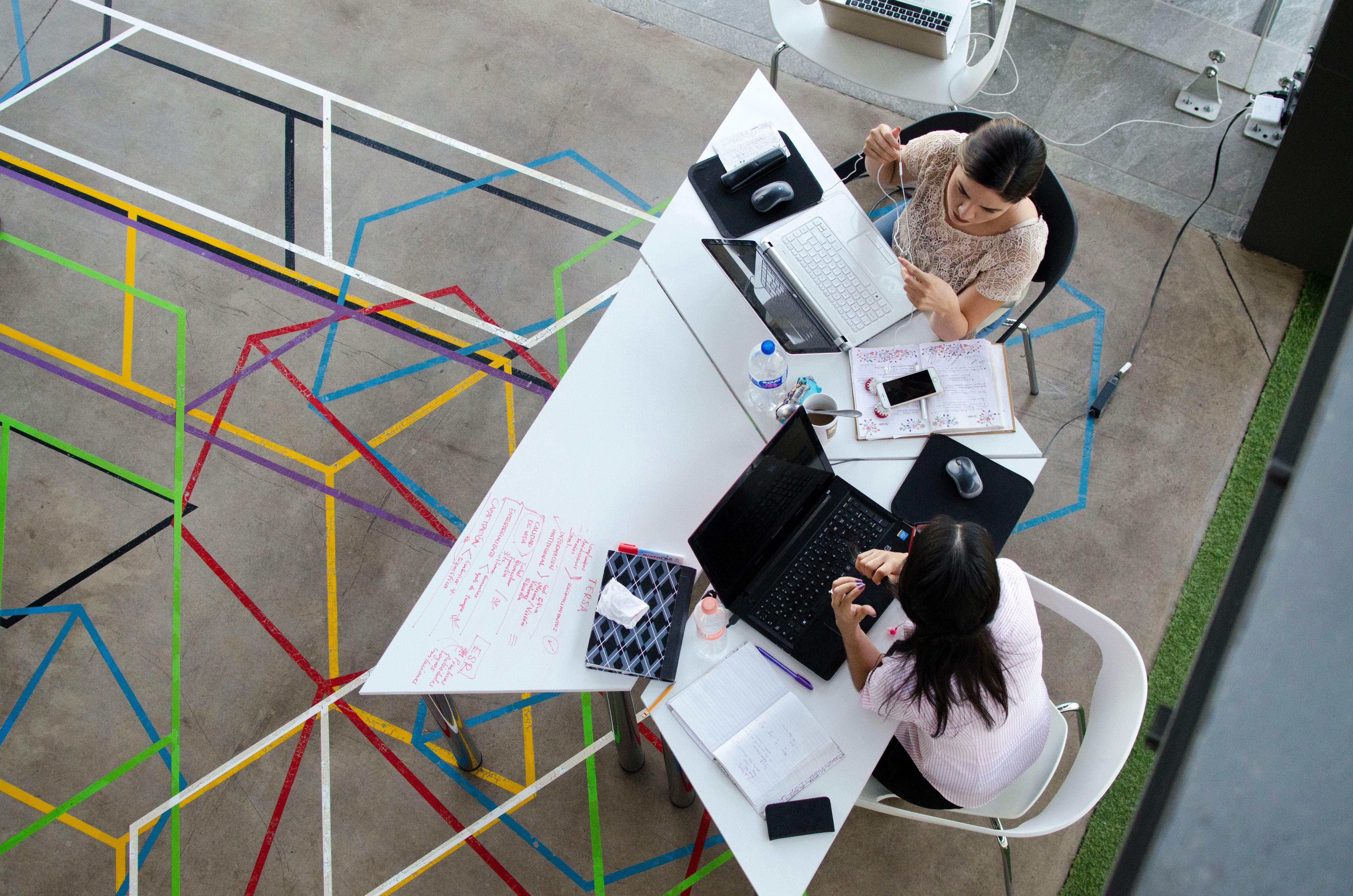 two women sitting in chairs using laptop computers