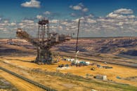 鸟瞰图中，重型机械在多云天空下的大型露天矿井里作业