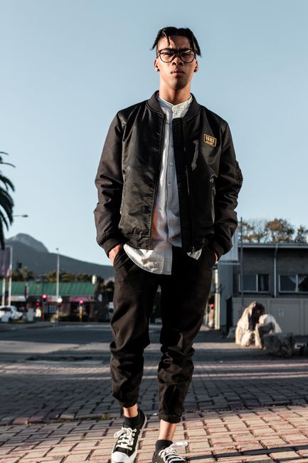 Fashionable young man wearing a jacket and glasses posing in George, South Africa.