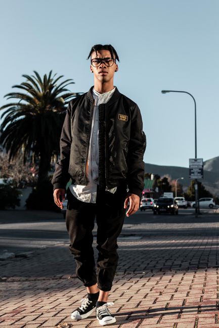Fashionable young man in trendy streetwear standing confidently outdoors, showcasing urban style.