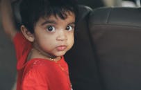 孩子睁着可爱的大眼睛，坐在车里直视着摄像机