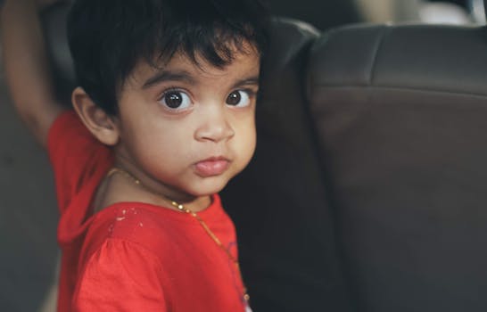 孩子睁着可爱的大眼睛，坐在车里直视着摄像机