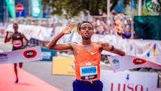 为庆祝马拉松胜利，一名跑步者冲过了街头色彩缤纷比赛的终点线