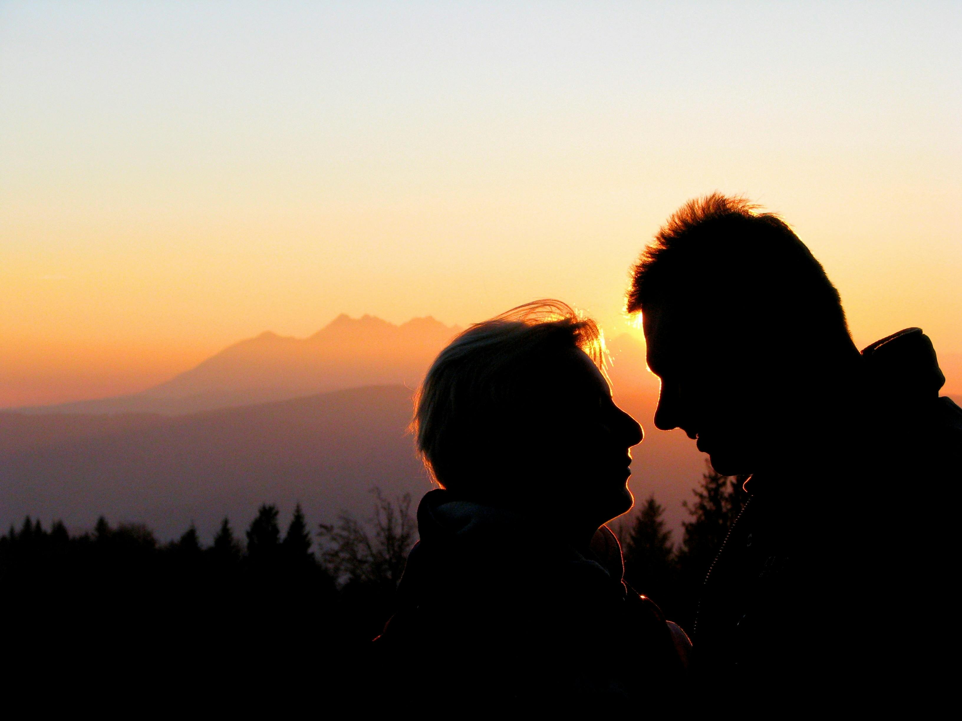 日没時に空にキスするシルエットカップル 無料の写真素材