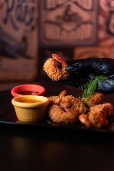 Close-up shot of fried shrimp with sauces served on a dark plate, perfect for a gourmet meal.