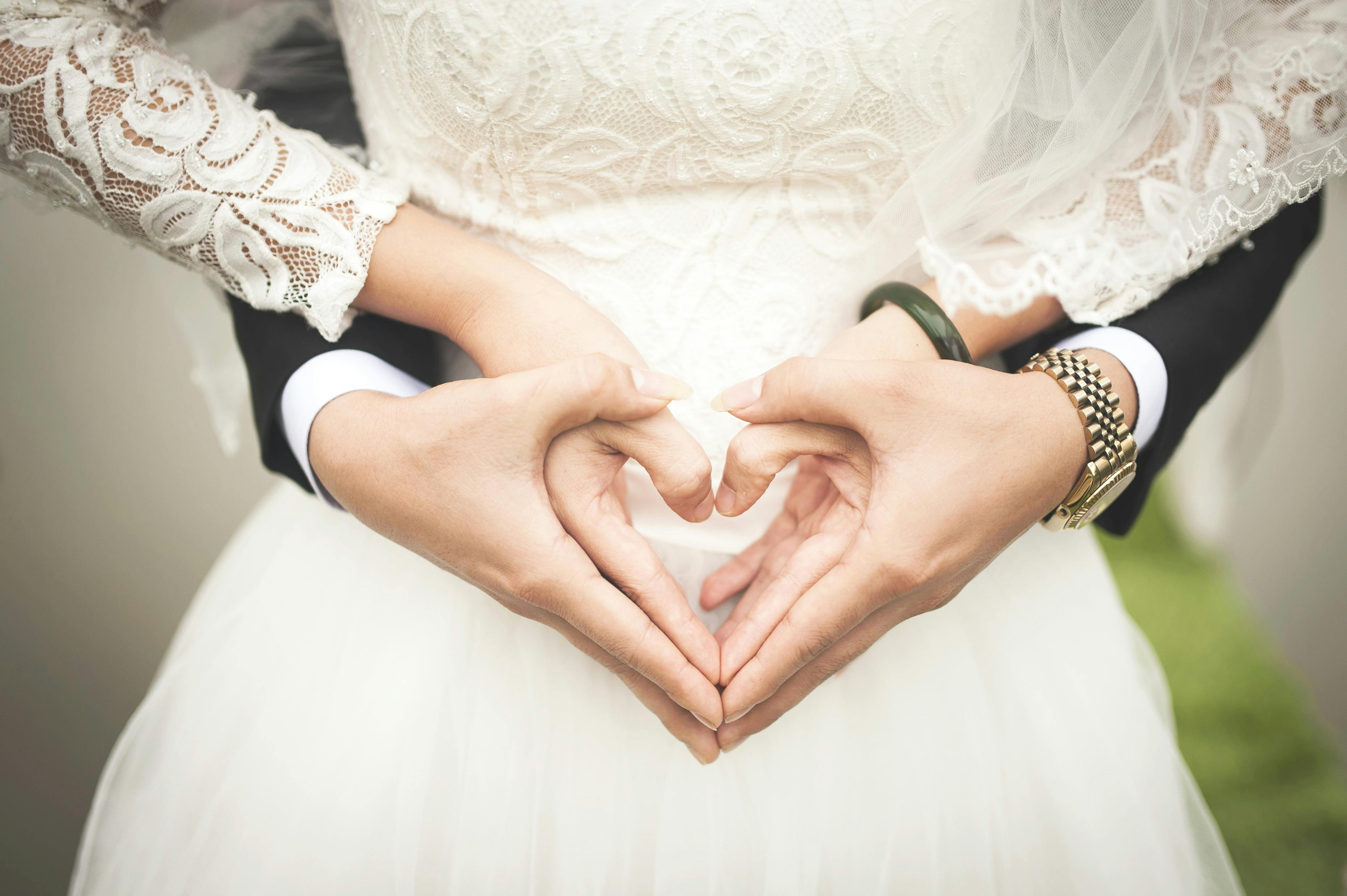 Man and woman making a heart shape with their hands. | Photo: Pexels