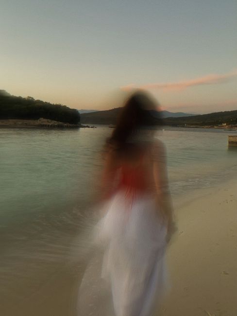 Blurry silhouette of a woman walking along Ksamil beach at sunset, creating a dreamy atmosphere.